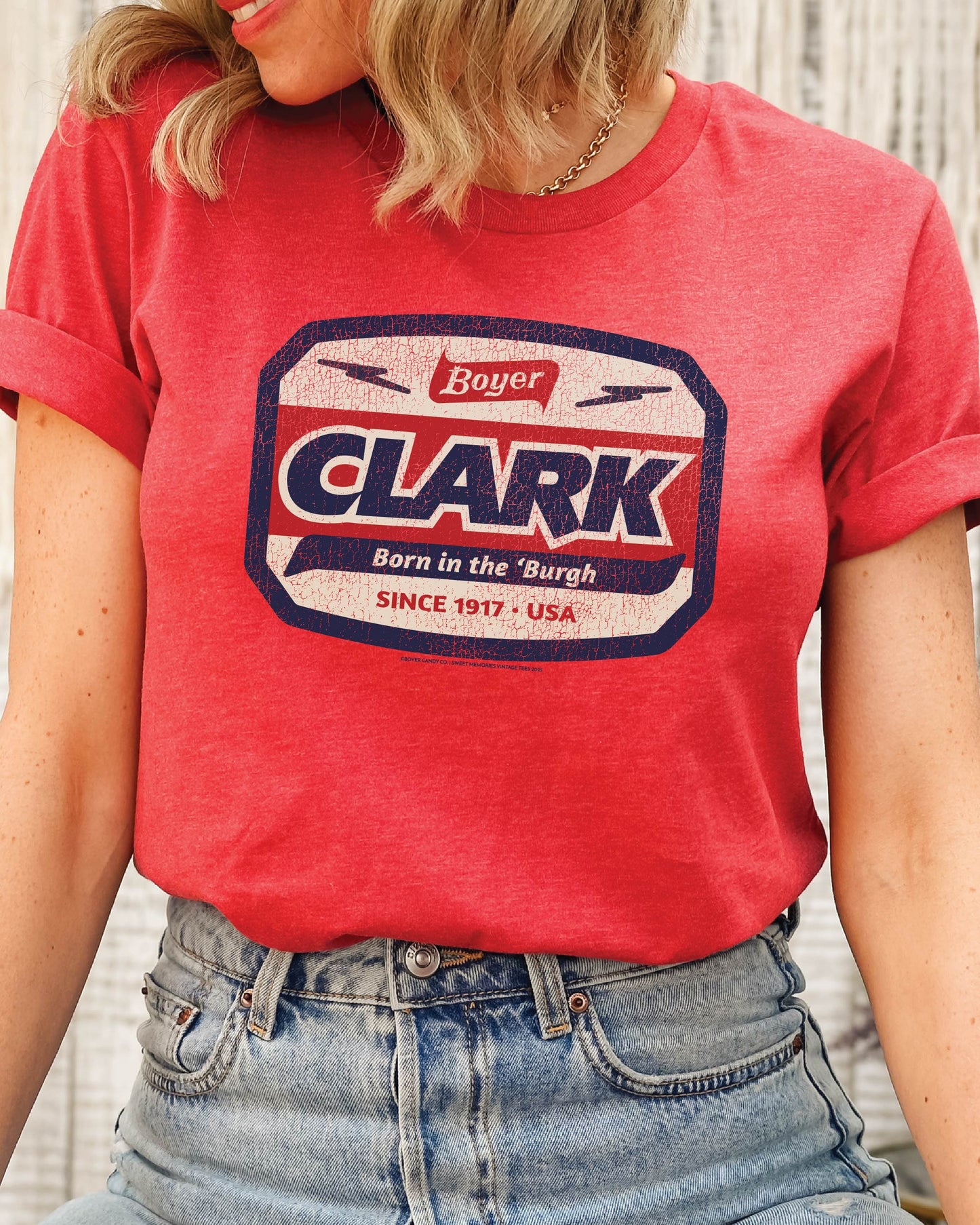 Woman wearing the officially licensed Boyer® Clark Bar® Born in the 'Burgh vintage candy unisex graphic T-shirt featuring a retro Pittsburgh pride design.