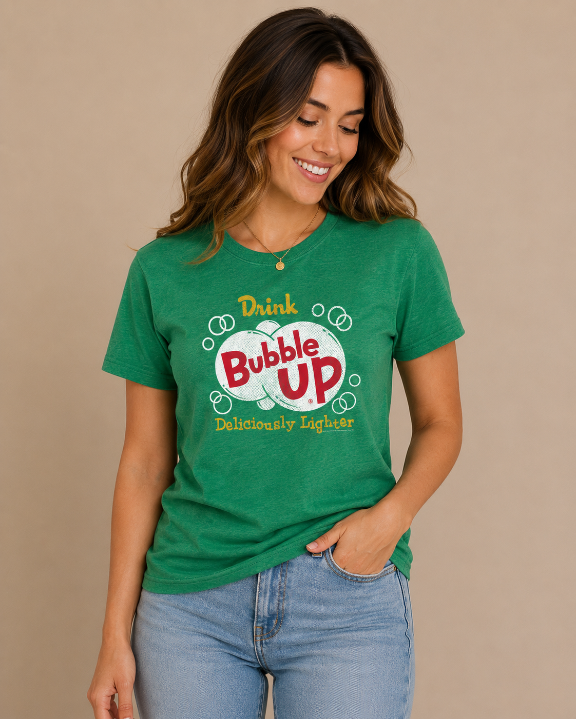 Woman wearing the Bubble Up® Deliciously Lighter Tee in heather green featuring a vintage Bubble Up soda graphic on a neutral studio background.