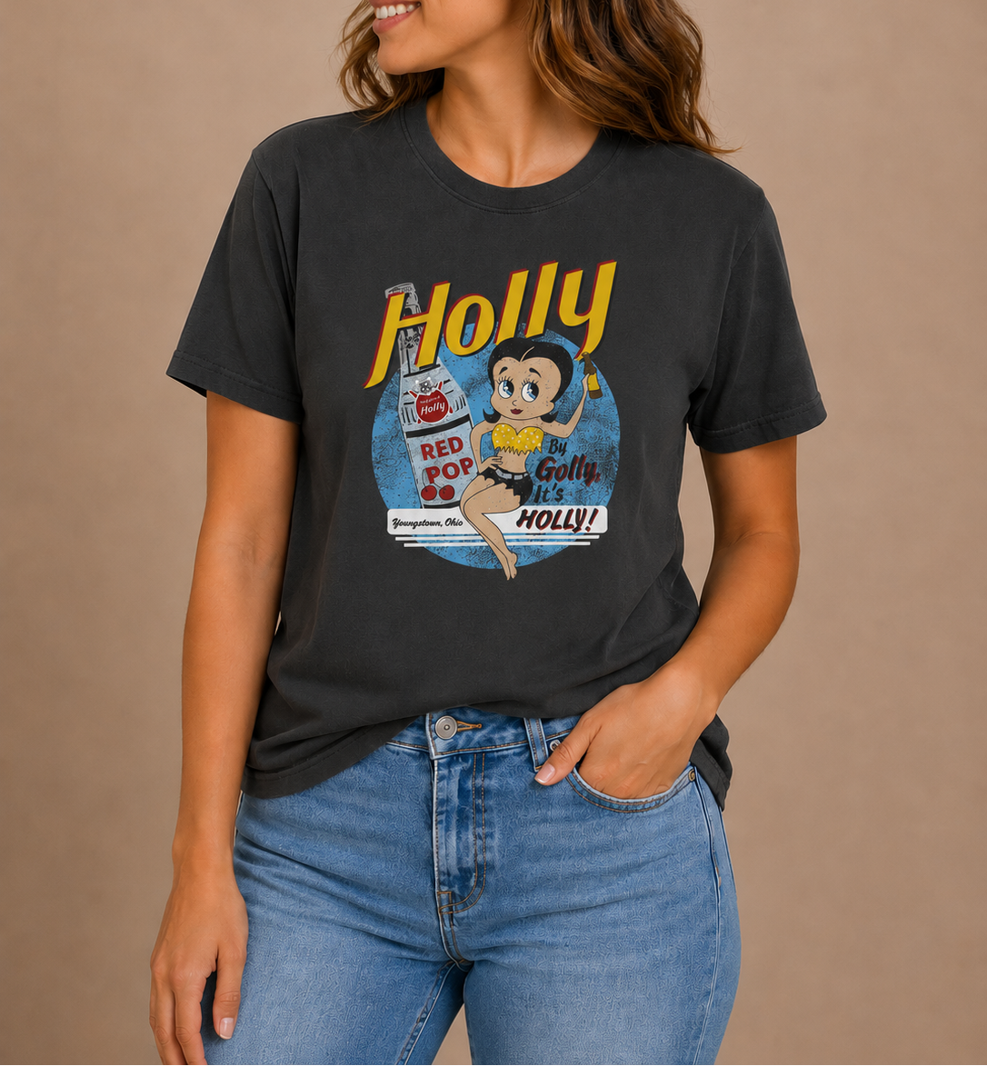 Woman wearing the By Golly, It's Holly! Tee featuring nostalgic Holly soda branding and retro-inspired artwork.