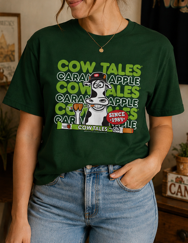 Female model wearing the Goetze's Cow Tales Caramel Apple Brand Colors graphic T-shirt styled with jeans for a casual fall look.