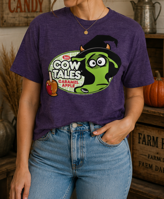 Female model wearing the purple Goetze's Cow Tales Caramel Apple Halloween Duke graphic T-shirt styled for fall and Halloween.