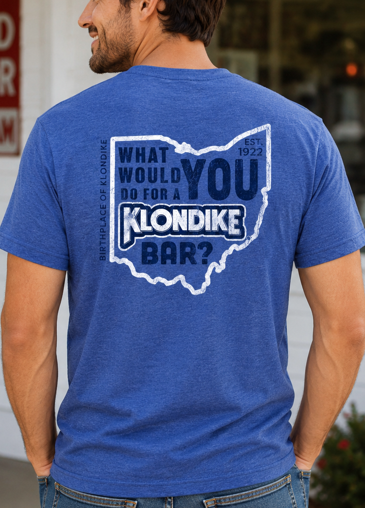 Male model wearing the Klondike® Birthplace of Klondike Ohio t-shirt with vintage chest logo on a blue heather tee.