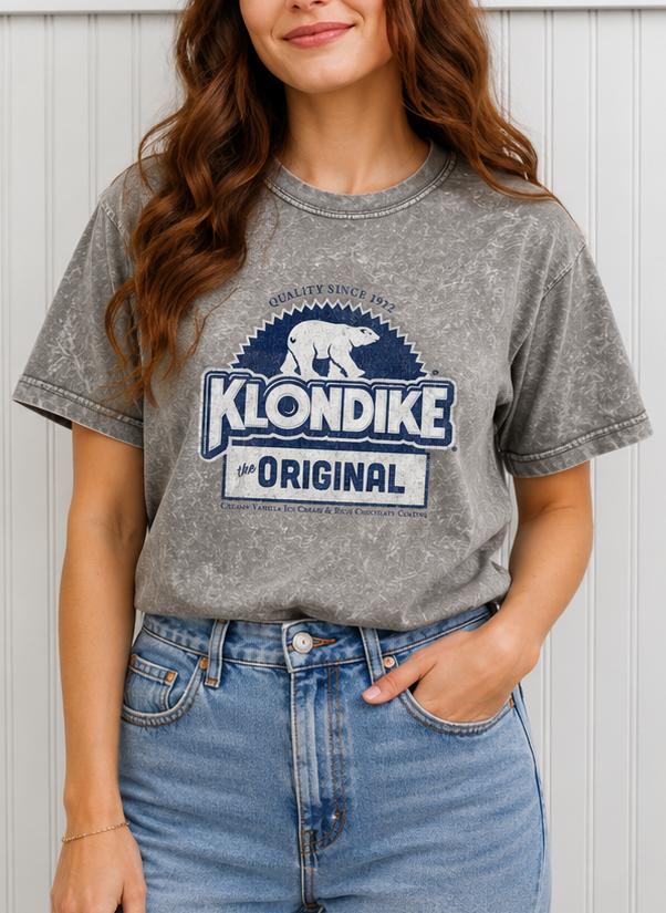 Woman wearing a Klondike® Foil Wrapper Since 1922 mineral wash t-shirt featuring the classic Klondike polar bear logo and vintage frozen treat graphic.