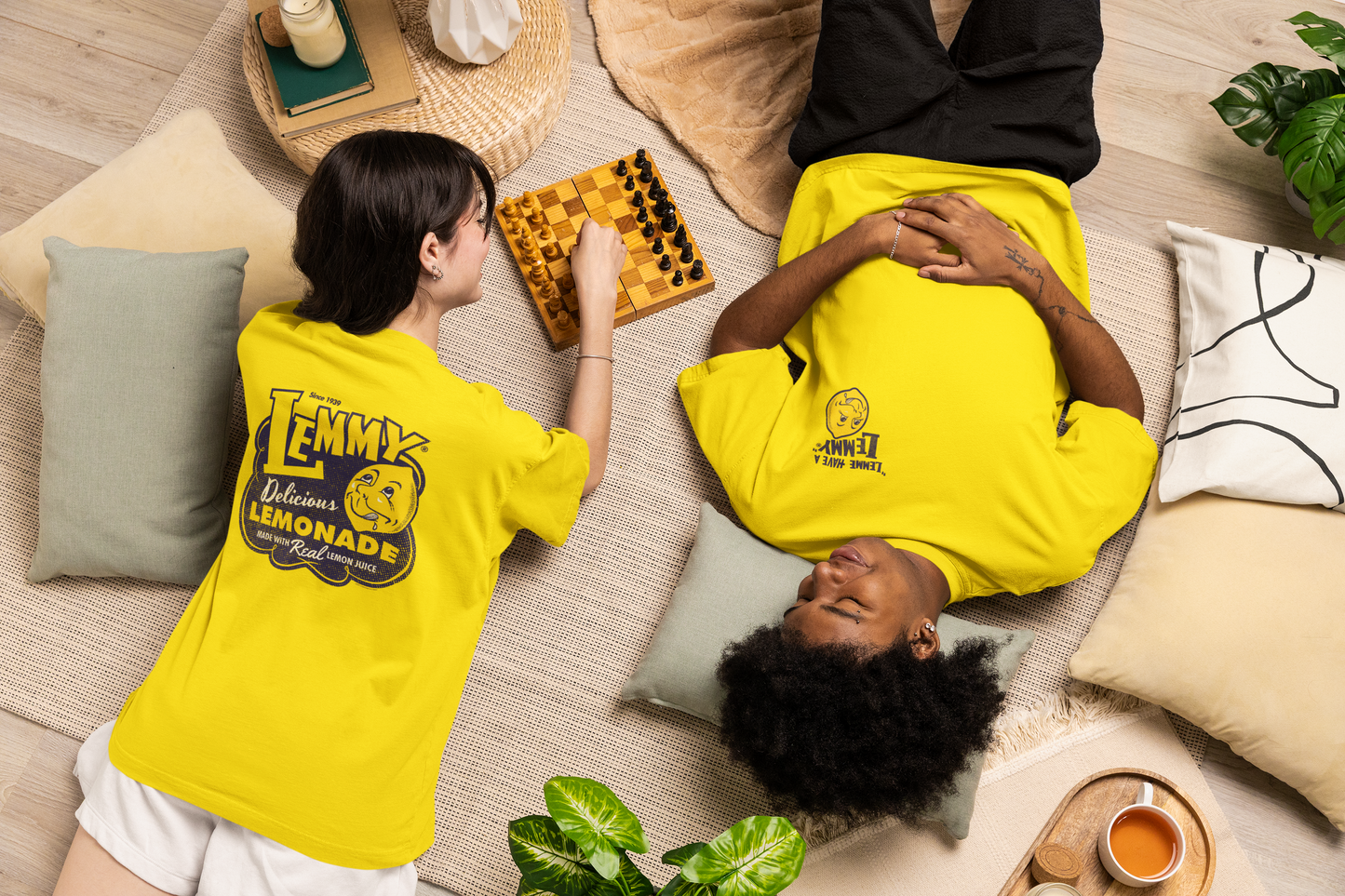 Male and female models wearing the Officially Licensed Lemmy® Lemonade Tee featuring the vintage Lemmy® front left chest logo on bright yellow unisex graphic T-shirts.