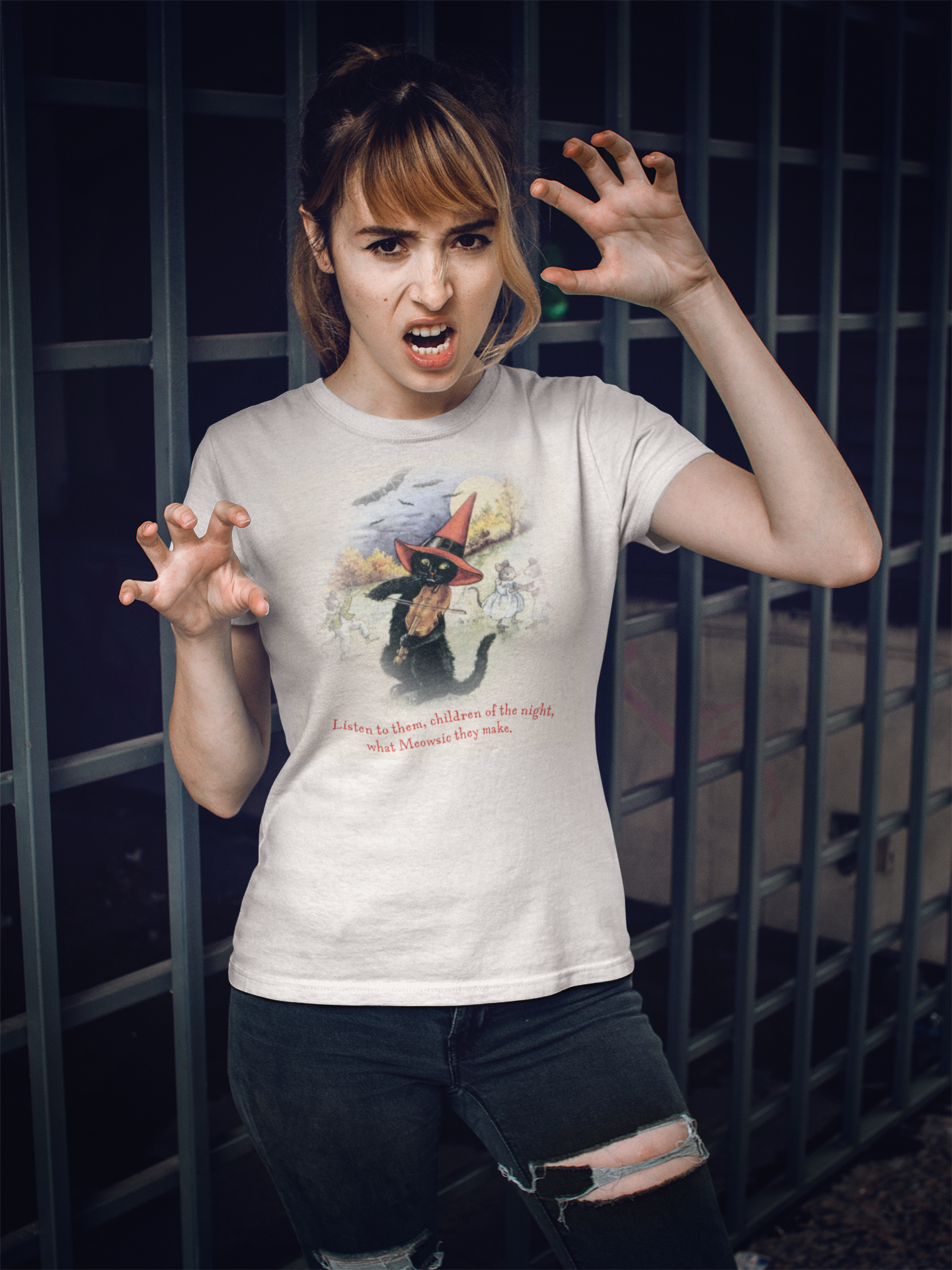 Female model wearing the Meowsic of the Night Sweet Memories Halloween Exclusive tee with a spooky Halloween background.