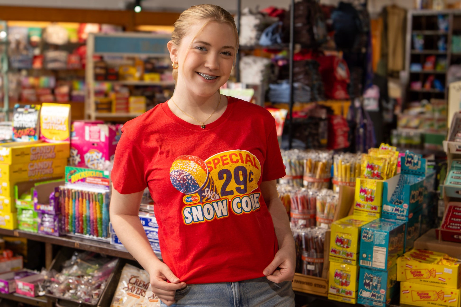 Female model wearing the Popsicle® Vintage Snow Cone Tee in heather red, showcasing a colorful retro Snow Cone design with nostalgic Popsicle artwork and vintage summer-inspired graphics.