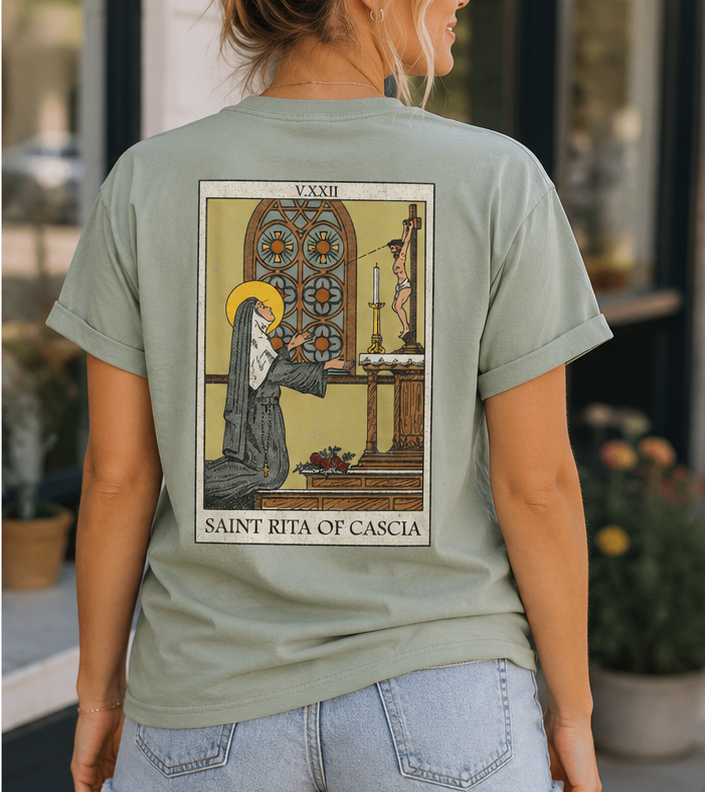 Woman wearing the back of the Saint Rita of Cascia unisex graphic T-shirt showcasing the vintage devotional artwork of Saint Rita in prayer.