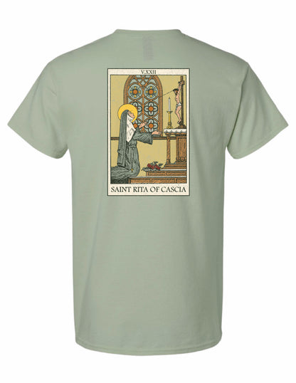 Back of the Saint Rita of Cascia unisex graphic T-shirt featuring vintage-inspired religious artwork of Saint Rita praying before the crucifix.