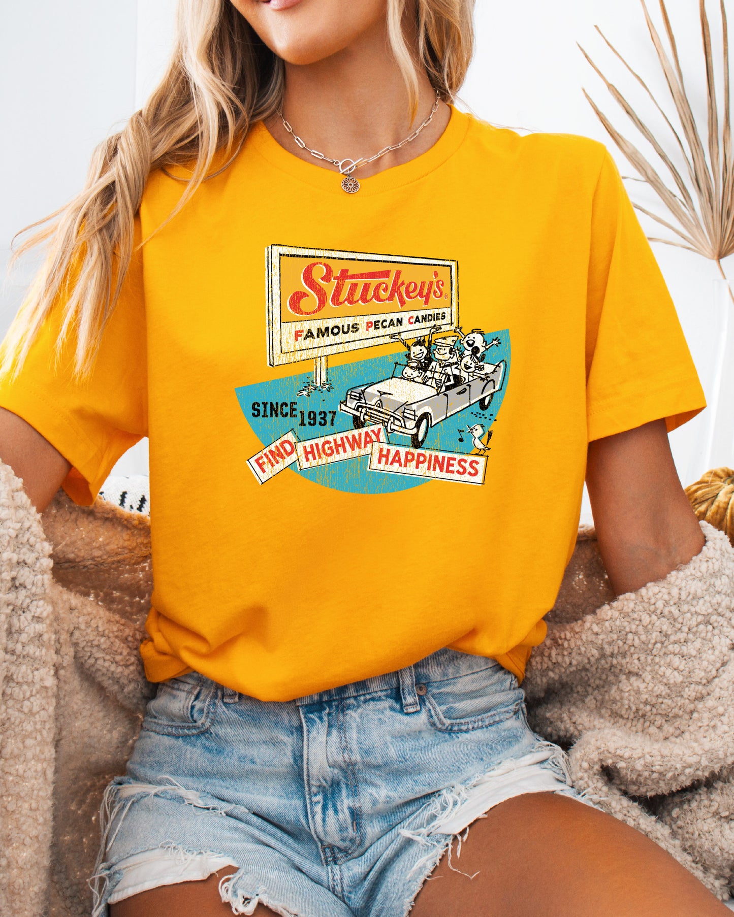 Female model wearing the Stuckey's® Find Highway Happiness Tee featuring nostalgic roadside graphics and classic Americana styling.