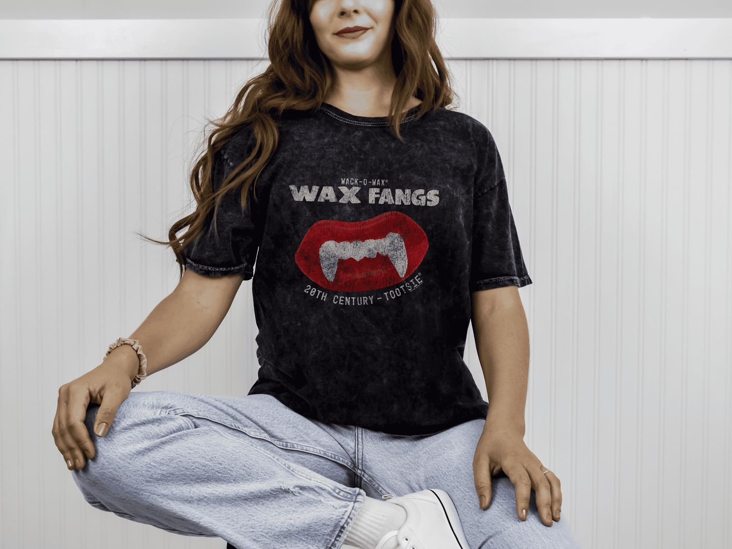 Woman wearing a Wack-O-Wax FANGS Black Mineral Wash Tee featuring nostalgic wax vampire fangs candy artwork.