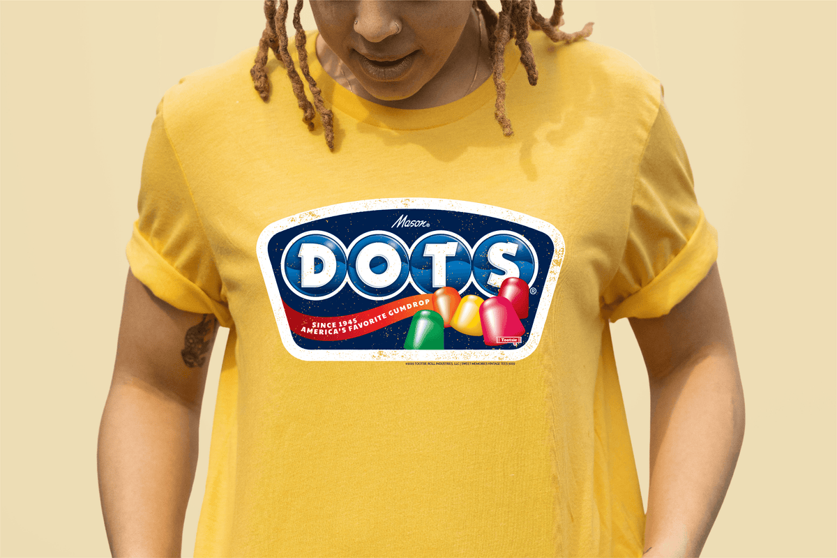 Model wearing the DOTS® Retro Gumdrops Unisex Graphic T-Shirt featuring colorful vintage-inspired candy artwork and a nostalgic retro DOTS® logo design.