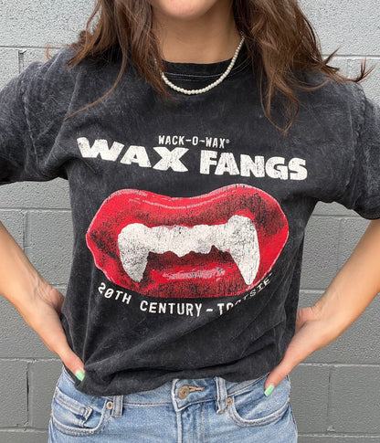 Woman wearing a Wack-O-Wax FANGS Black Mineral Wash Tee featuring nostalgic wax vampire fangs candy artwork.